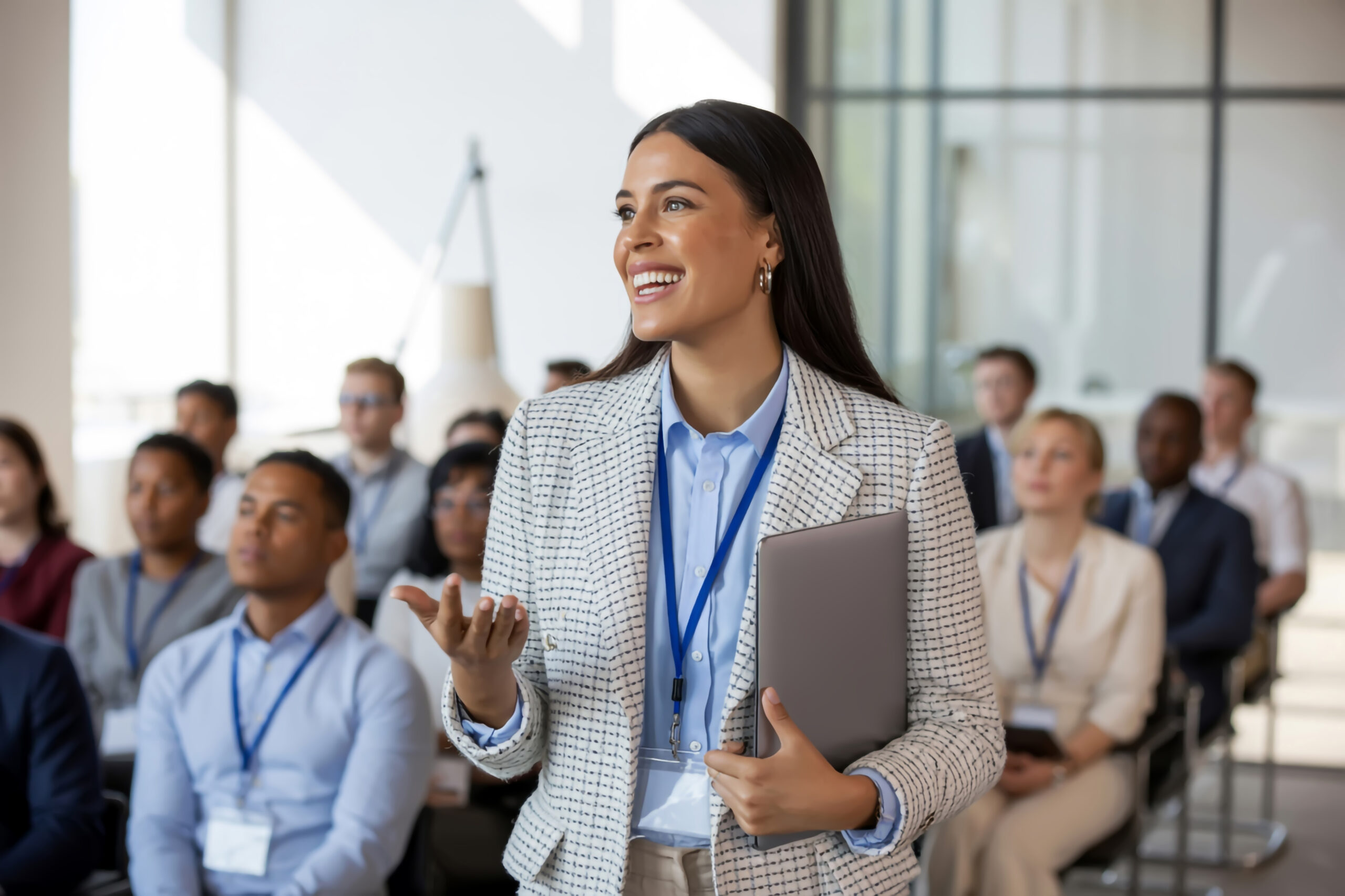Referentin spricht lächelnd vor interessiertem Publikum bei Seminar.